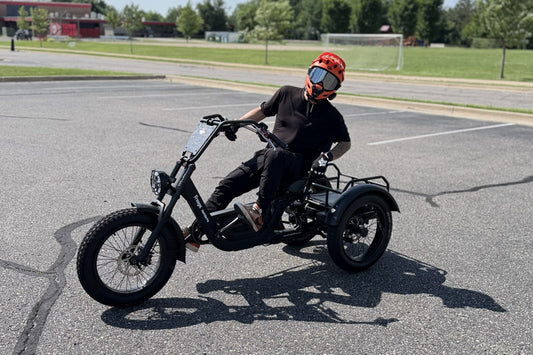 Rider on the electric trike with backrest turning in a paved parking area.