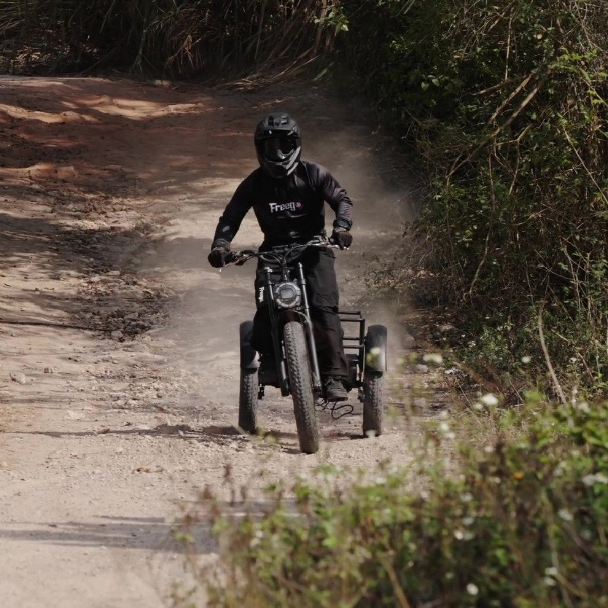 Person riding a freego flextrike swing on a dirt road surrounded by trees and plants.