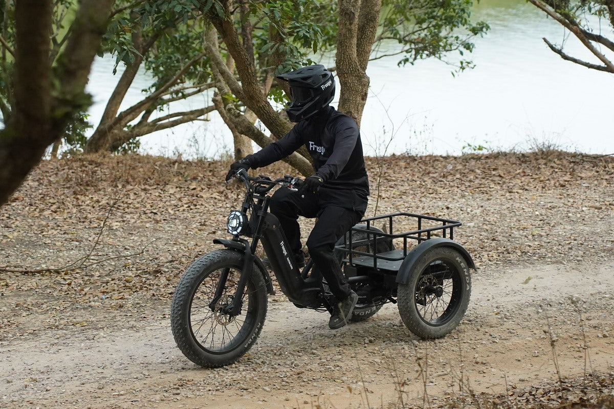 Person riding a flektrike swing on a dirt path with trees and water in the background