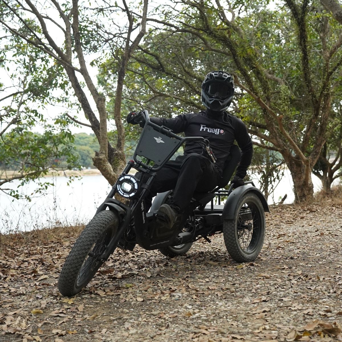 Person riding a freego flextrike pro in a natural setting with trees and water.