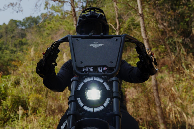 Person on a freego flextrike pro with a large screen displaying a brand logo, surrounded by trees.
